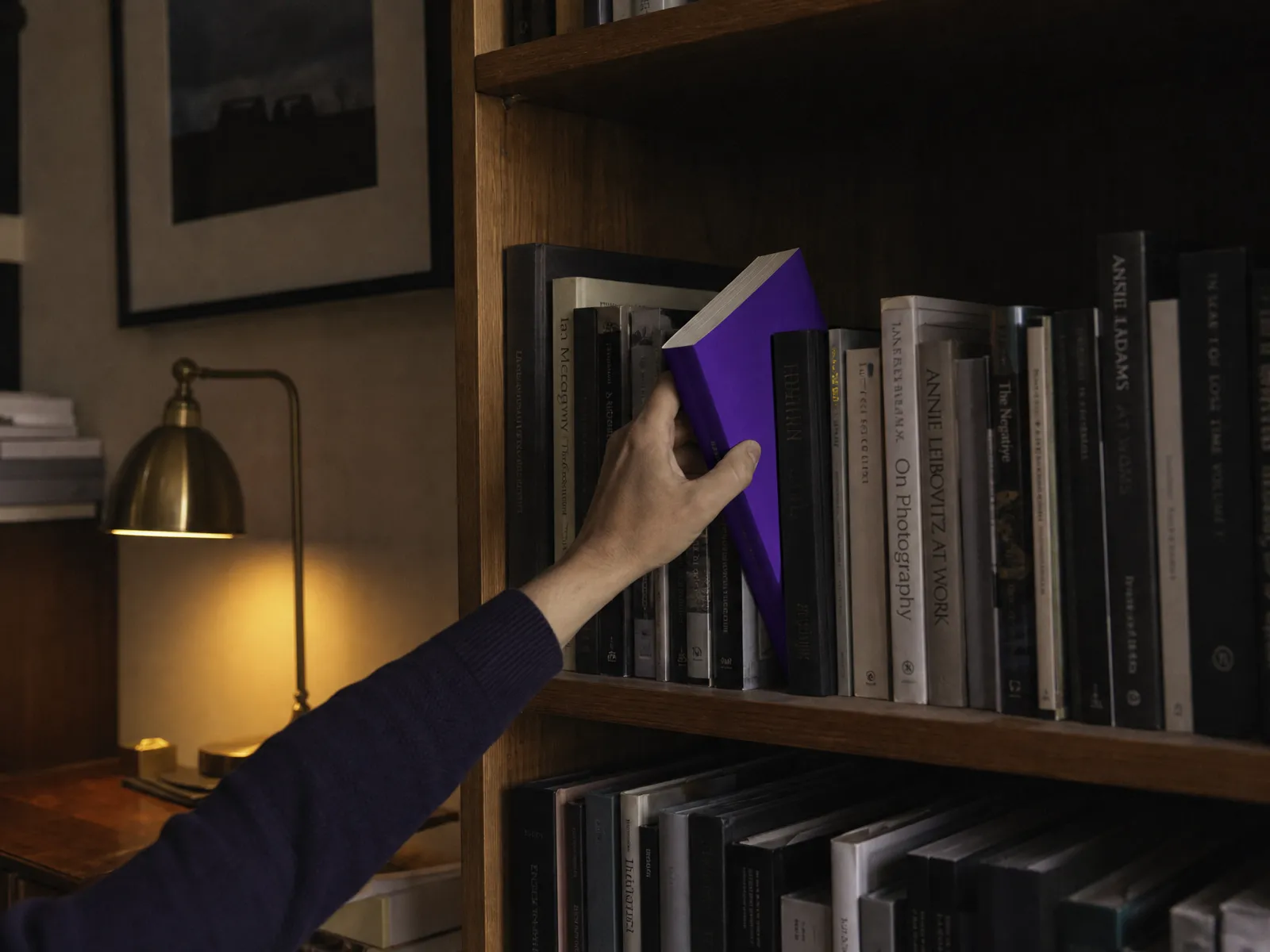 A quiet study with a bookshelf and a single lamp, a hand lifting one book with a violet spine, illustrating trust and expertise in AI in SEO.
