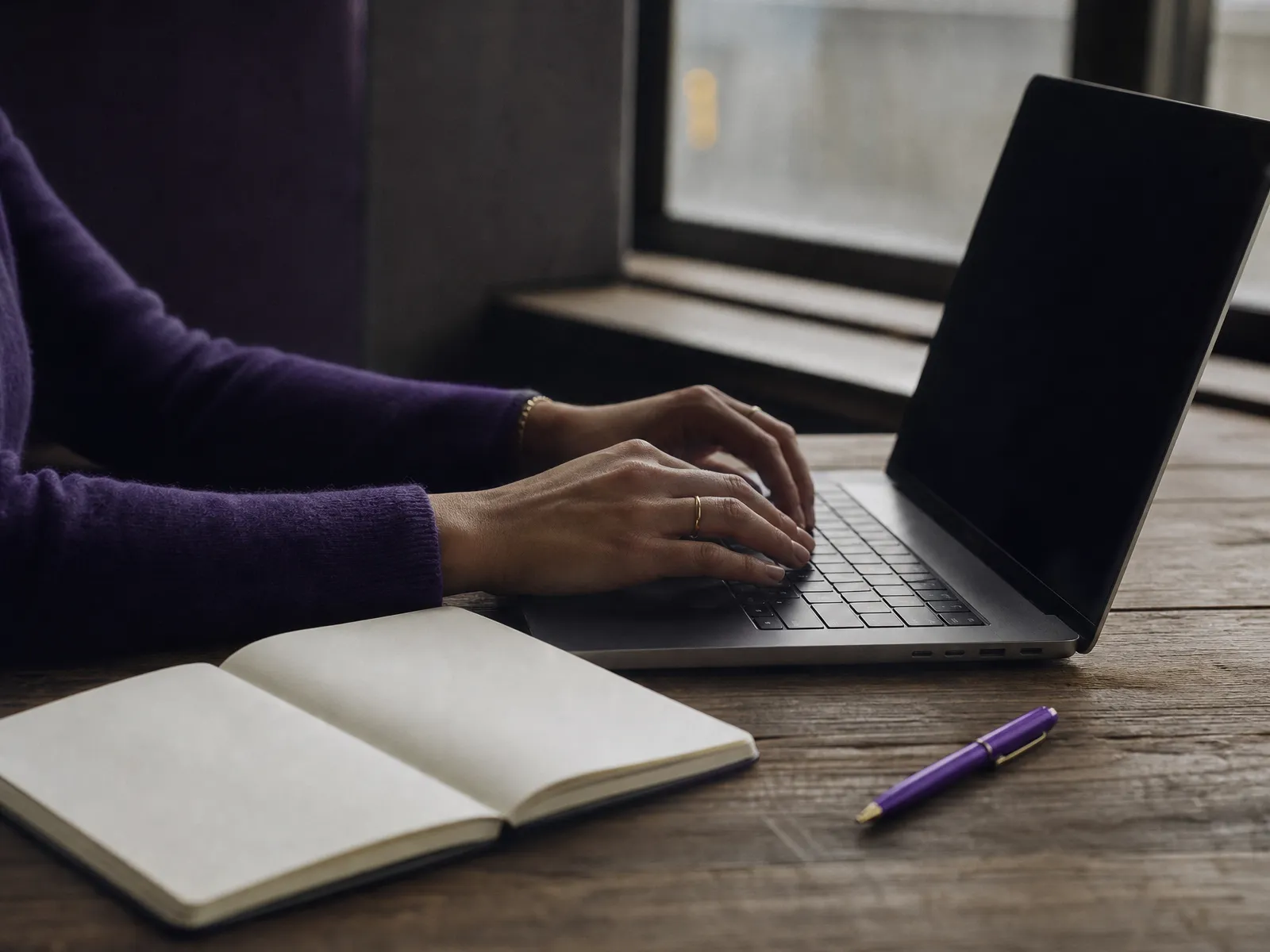 Hands resting on a laptop keyboard beside an open notebook in soft daylight, illustrating backlink building seo groundwork.