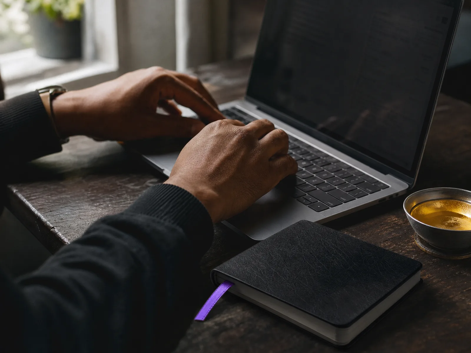 Hands at a wooden desk composing a review reply on a laptop keyboard