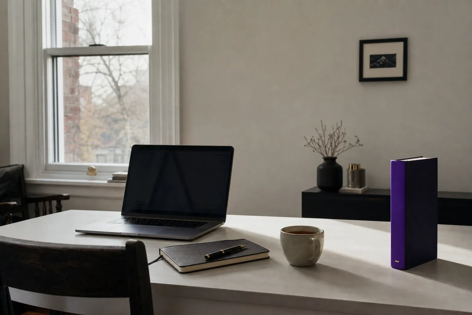 A quiet home-office desk in soft daylight with a laptop, notebook and violet book spine, illustrating link building.