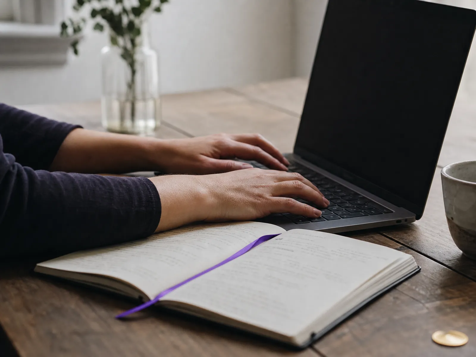 Hands resting on a laptop keyboard beside an open notebook in soft daylight, illustrating link building groundwork.