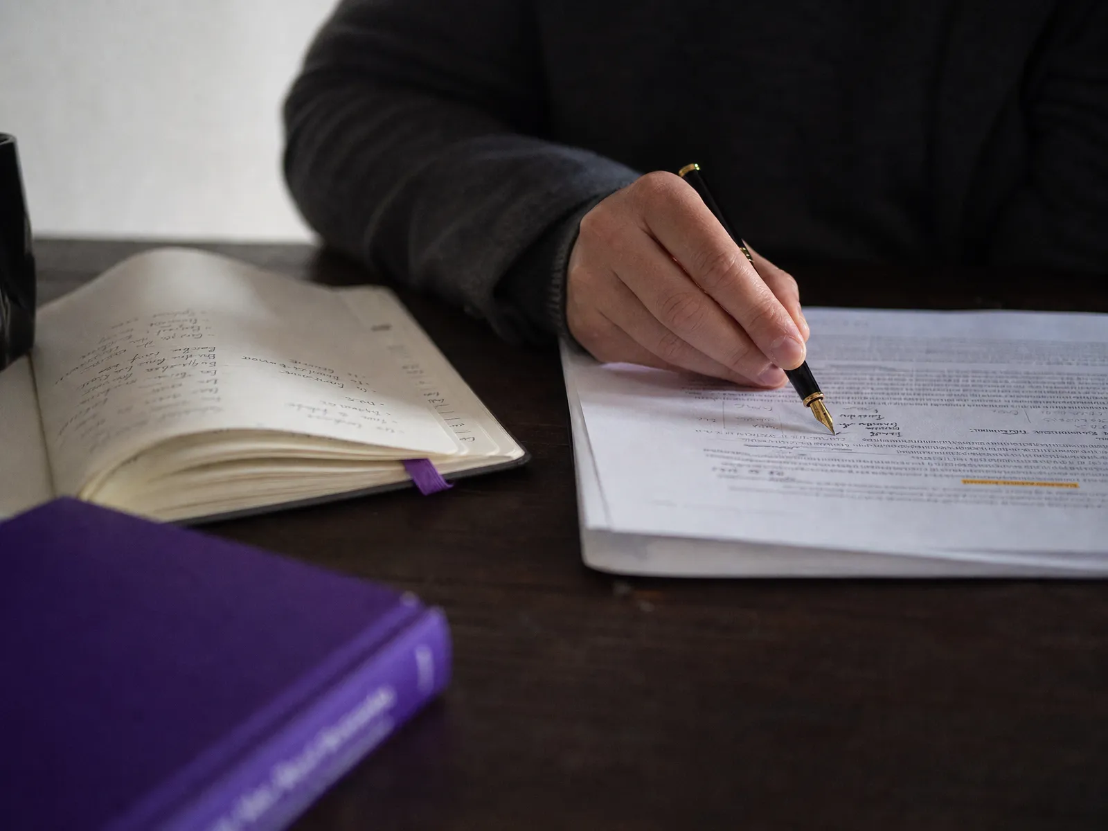 A hand annotating a printed report beside a notebook with a violet bookmark, illustrating a careful link building review.
