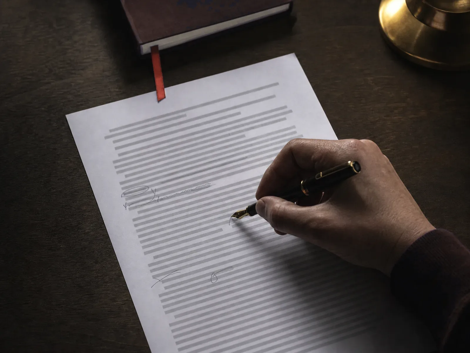 Hand annotating a printed page with a fountain pen under a brass lamp