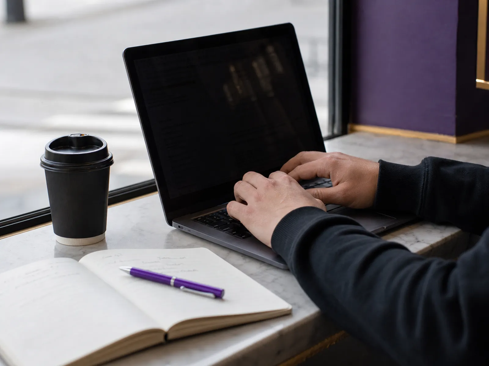 Hands typing on a laptop at a small business counter in soft daylight, planning seo marketing for small business
